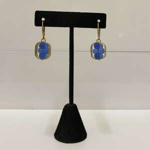 Elegant earrings with two rows of blue stones, set in a gold frame, displayed on a black stand against a neutral background. Minimalist design.