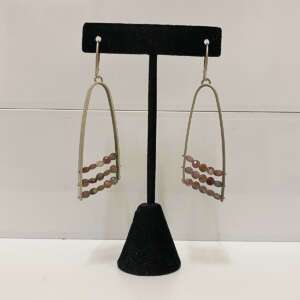 Elegant silver teardrop earrings with three rows of small, round pink beads. Displayed on a black stand against a neutral background.