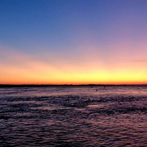 Print of the ocean during sunset. The sky is orange and purple.